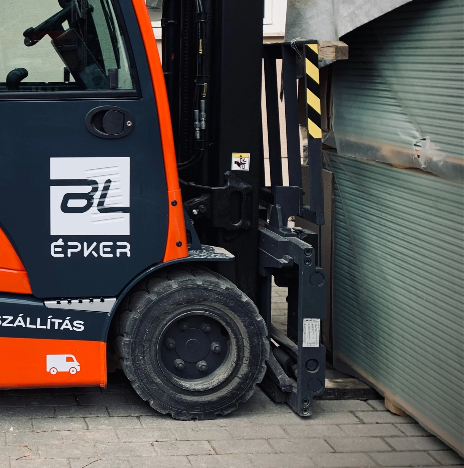 BL Épker targonca részlet – BL ÉPKER vállalati logó és a villás emelő integrált sárga-fekete biztonsági figyelmeztető csíkjai
