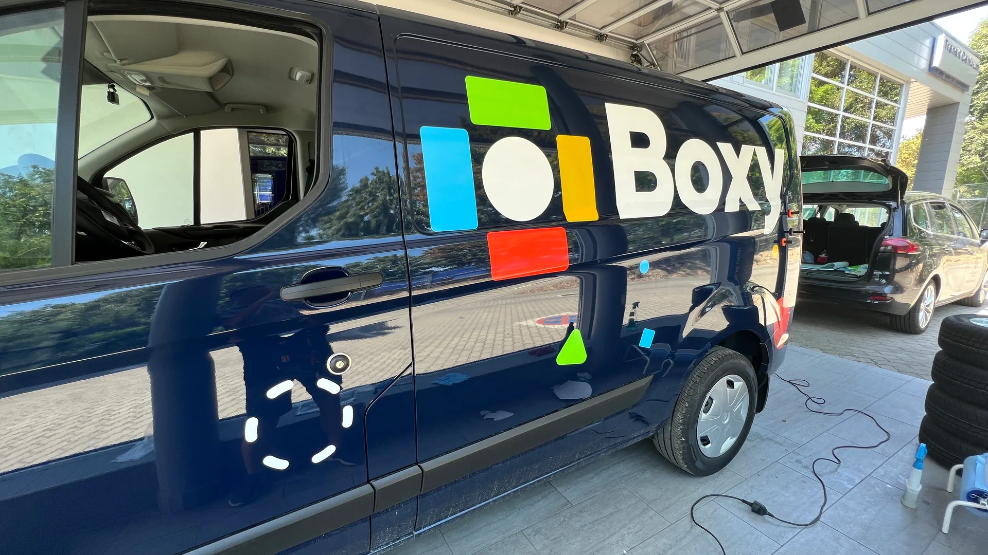 Boxy Ford Transit Custom oldal-dekor telepítés utáni állapot – Boxy logó és színes geometrikus formák felhelyezve a sötétkék karosszériára