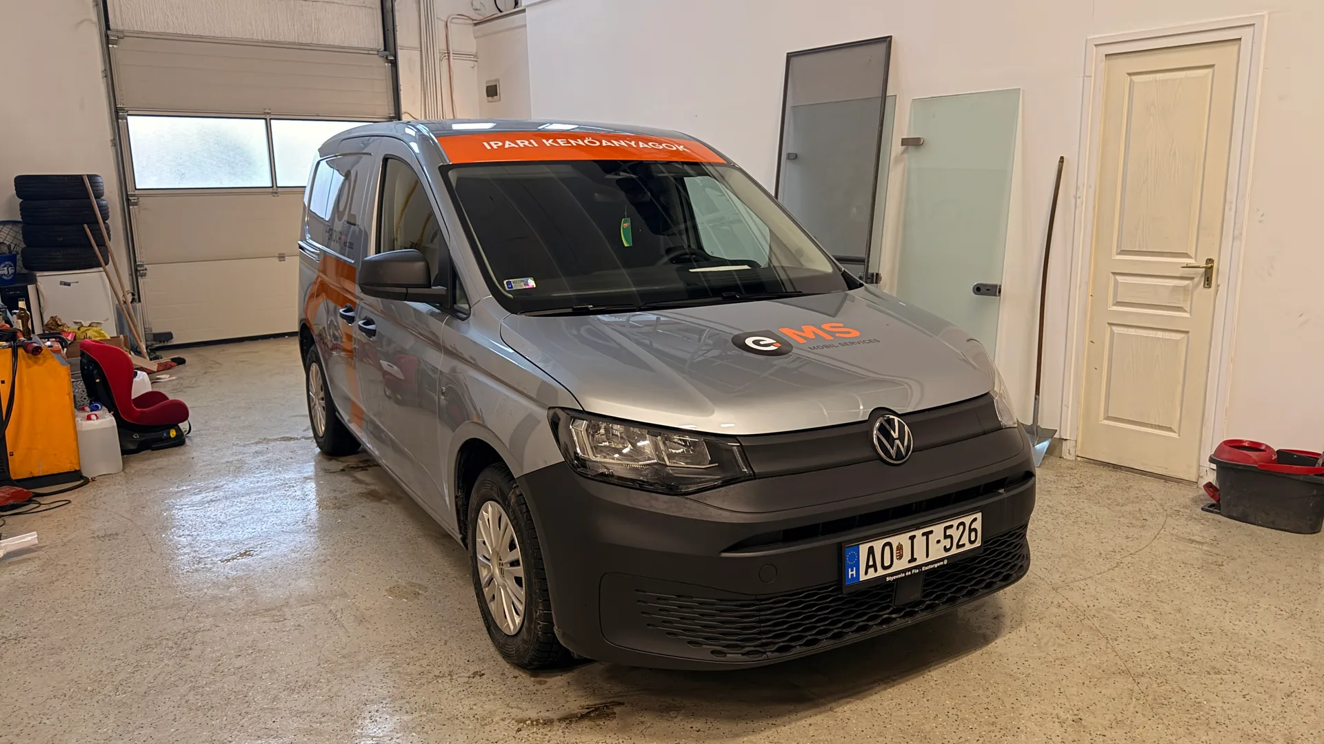 Ecool Volkswagen Caddy elülnézet háromnegyedes szögből – IPARI KENŐANYAGOK felirat a szélvédő fölött, oldal-dekor részlete narancssárga D-motívummal