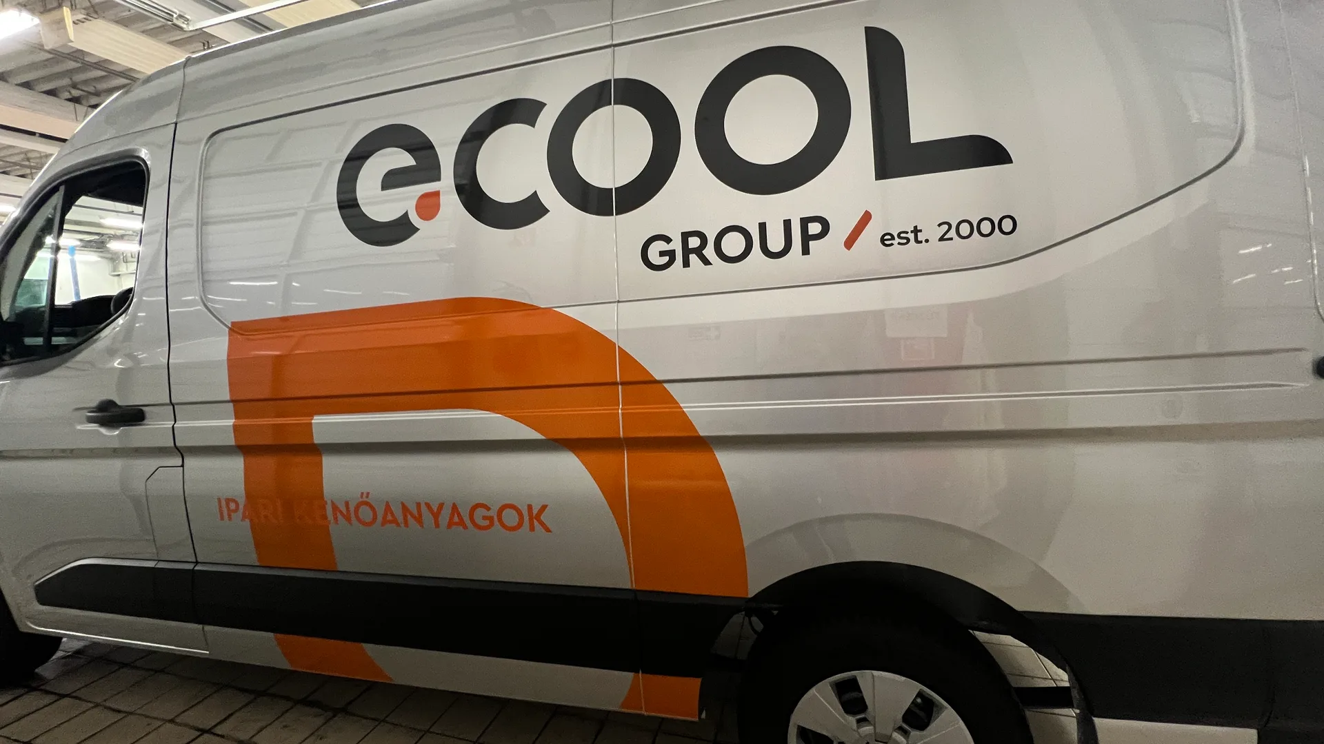 Ecool új arculat részlet a Renault Master oldalfalán – nagyméretű fekete e.COOL logó narancssárga pontmotívummal, GROUP est. 2000 felirat és bold narancssárga D-motívum