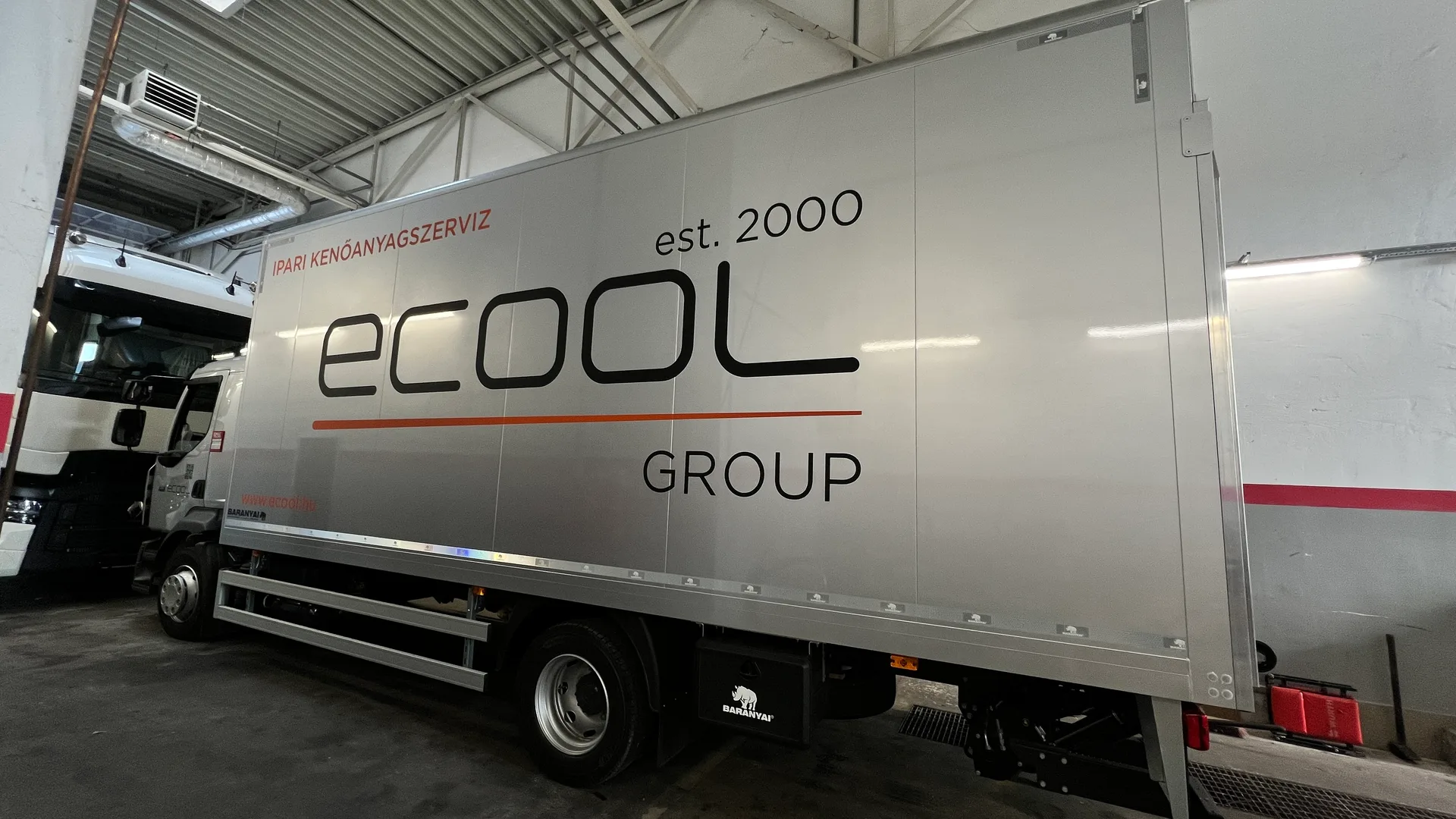 Ecool 12 tonnás dobozos felépítmény oldal-dekor részlet – nagyméretű fekete ecool logó, est. 2000, GROUP, narancssárga IPARI KENŐANYAGSZERVIZ felirat és vonalas grafikai elem