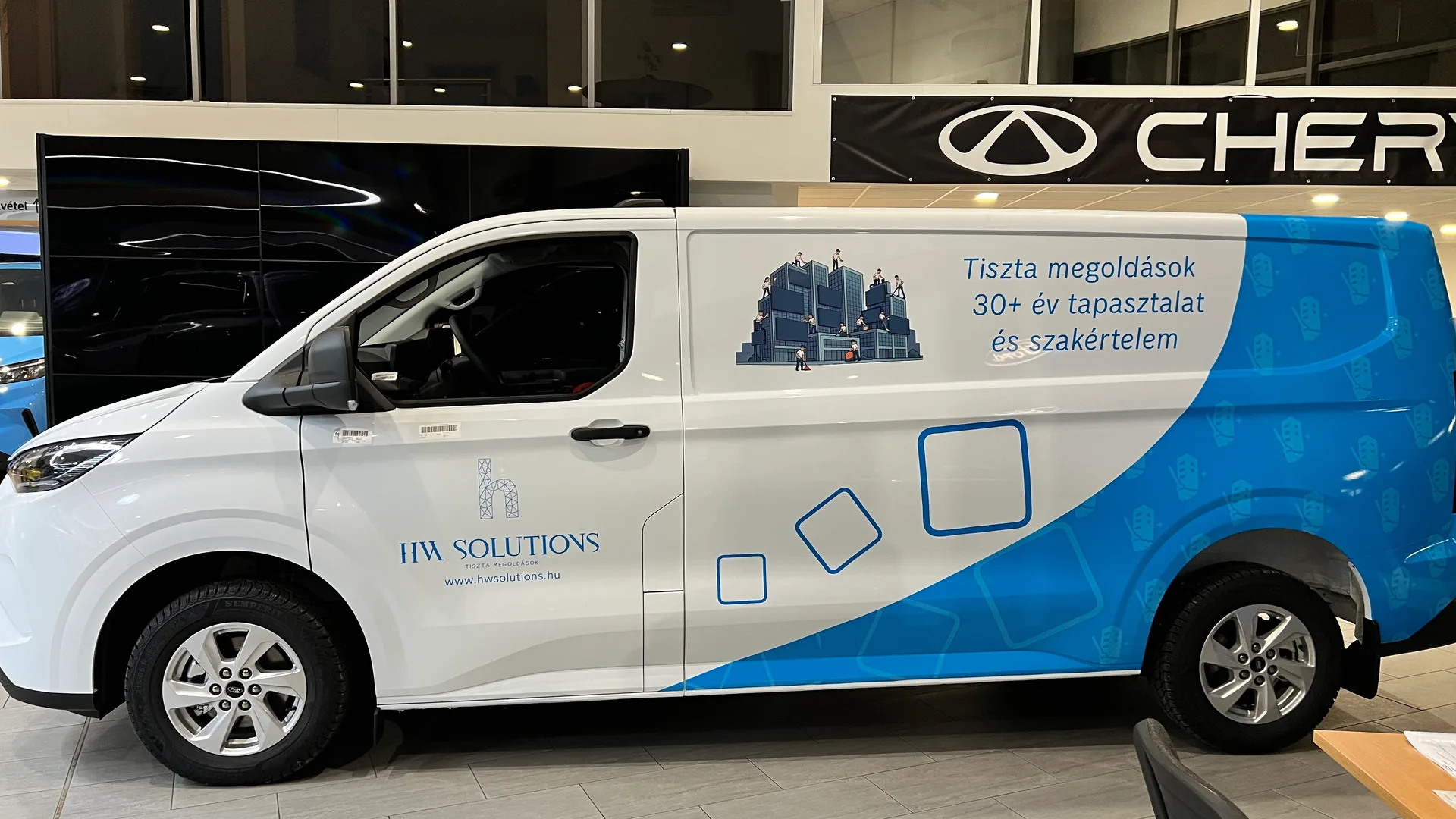 HW Solutions Ford Transit Custom járműdekoráció bal oldali nézet – nagyméretű kék hullámos vezérgrafika, középen az épülettisztítást ábrázoló illusztrációval és Tiszta megoldások szlogennel