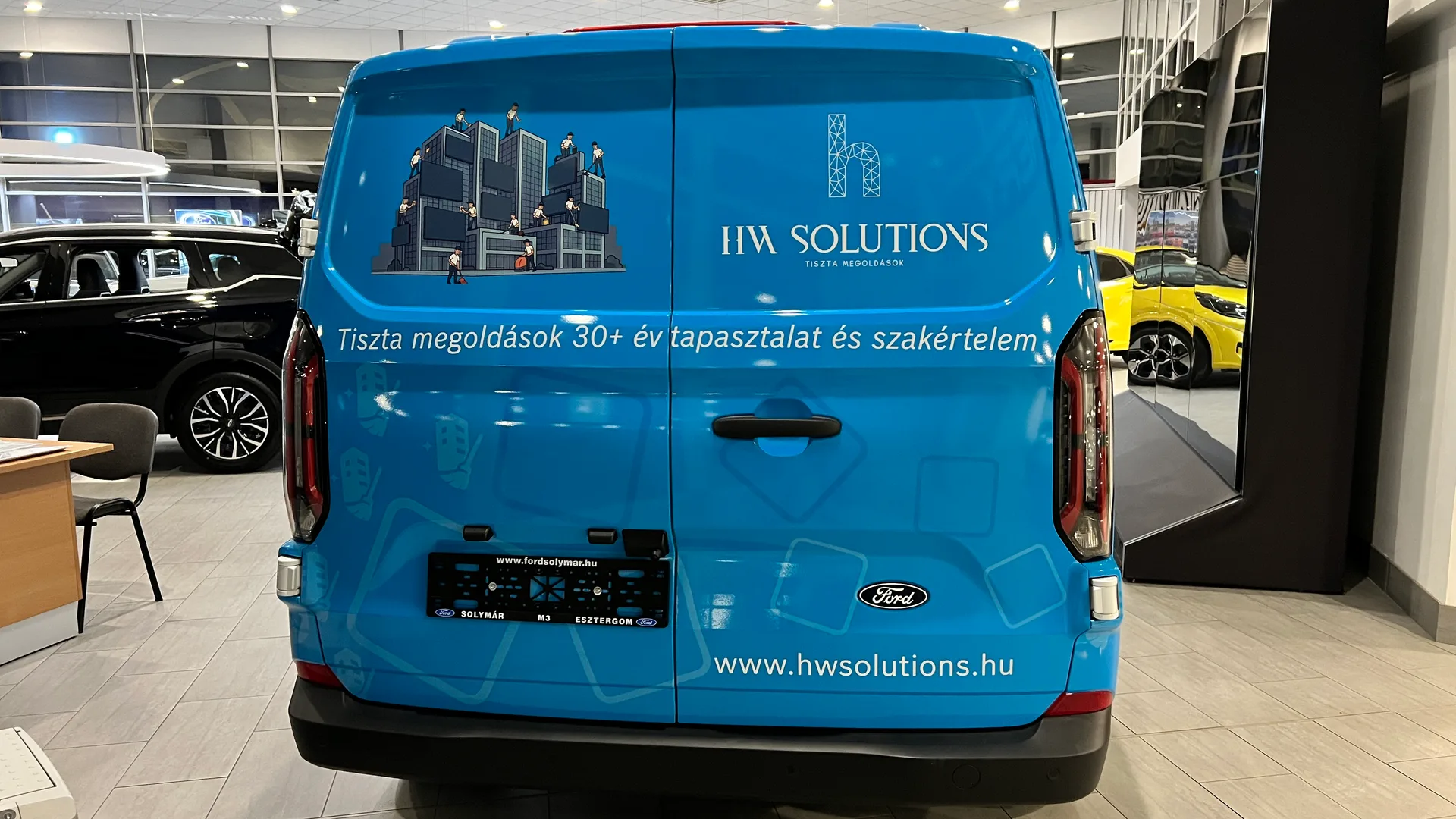 HW Solutions Ford Transit Custom járműdekoráció hátsó nézet – nagyméretű kék hátsó ajtó az épülettisztítás-illusztrációval, HW Solutions logóval, szlogennel és weboldallal