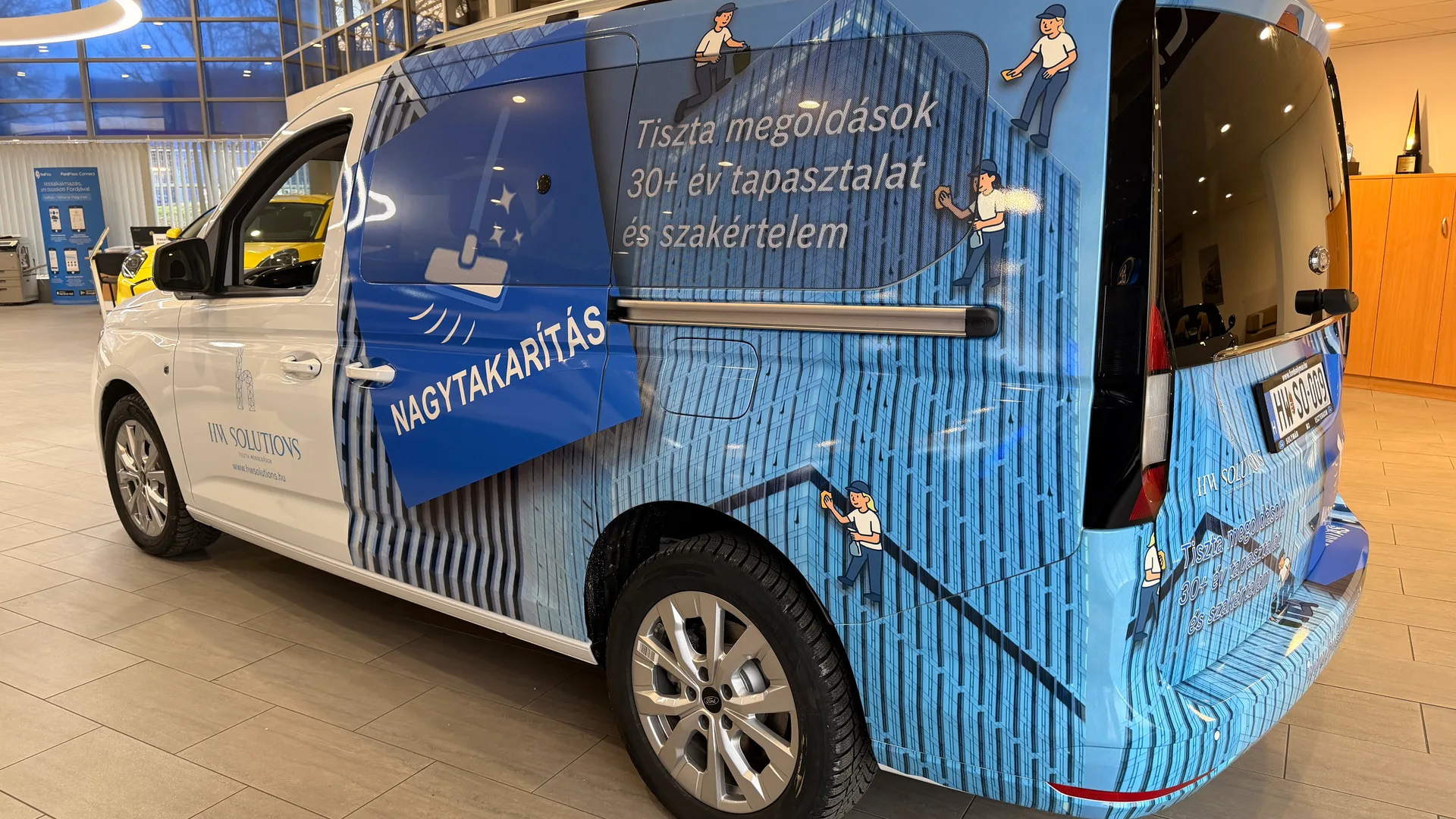 HW Solutions Ford Tourneo Connect közeli oldalnézet – épület-homlokzat grafikai részlet, takarítófigurák illusztrációi és Tiszta megoldások szlogen