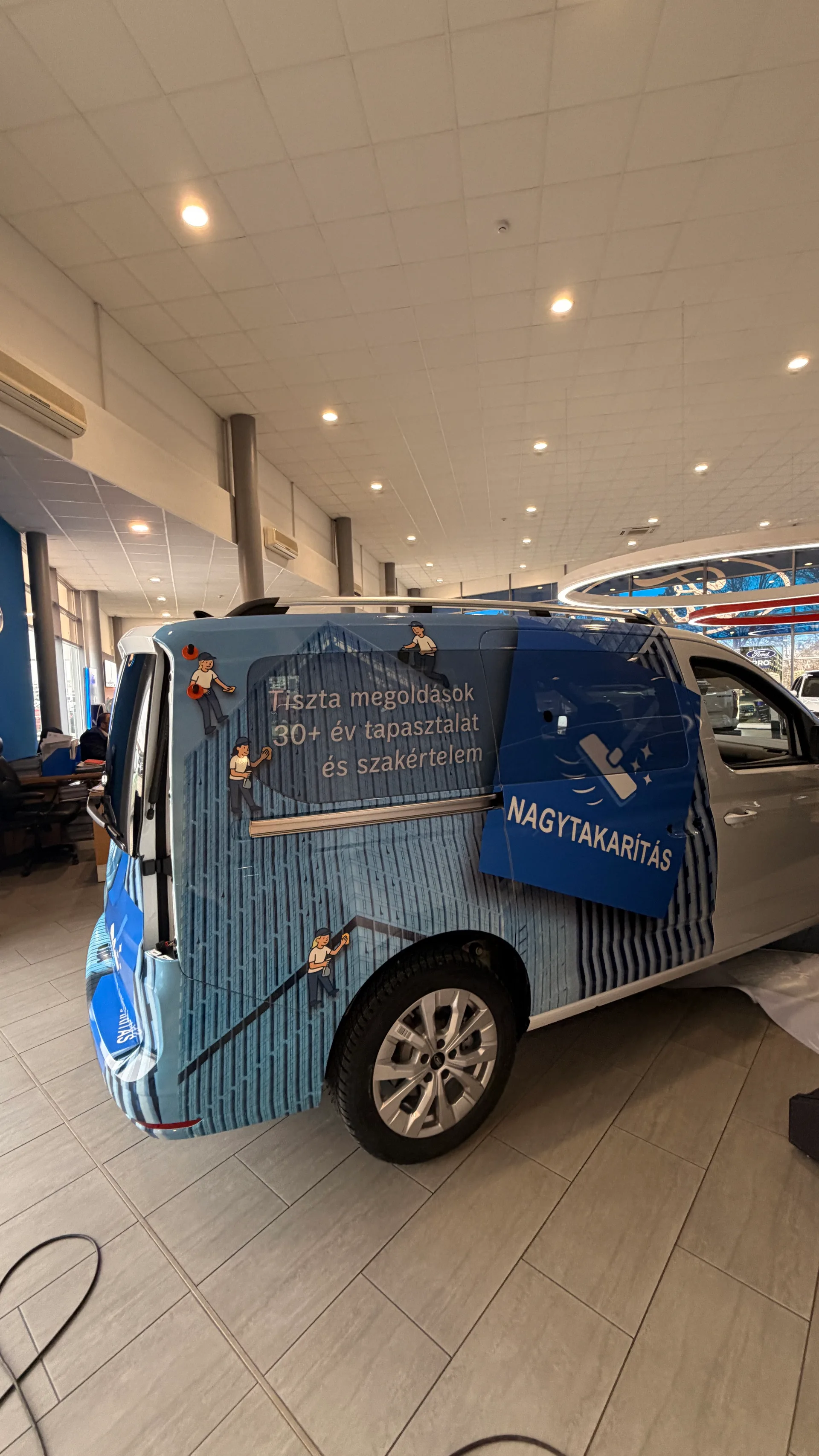 HW Solutions Ford Tourneo Connect oldalnézet portré formátumban – kék épület-homlokzat grafika, illusztrált takarítófigurák és kék NAGYTAKARÍTÁS elem