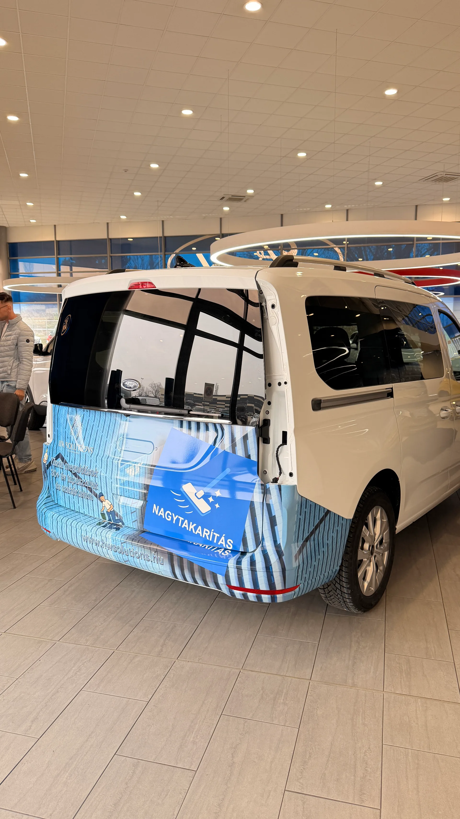 HW Solutions Ford Tourneo Connect hátsó nézet portré formátumban – hátsó ajtó dekorja a kék NAGYTAKARÍTÁS panellel és a hwsolutions.hu weboldallal