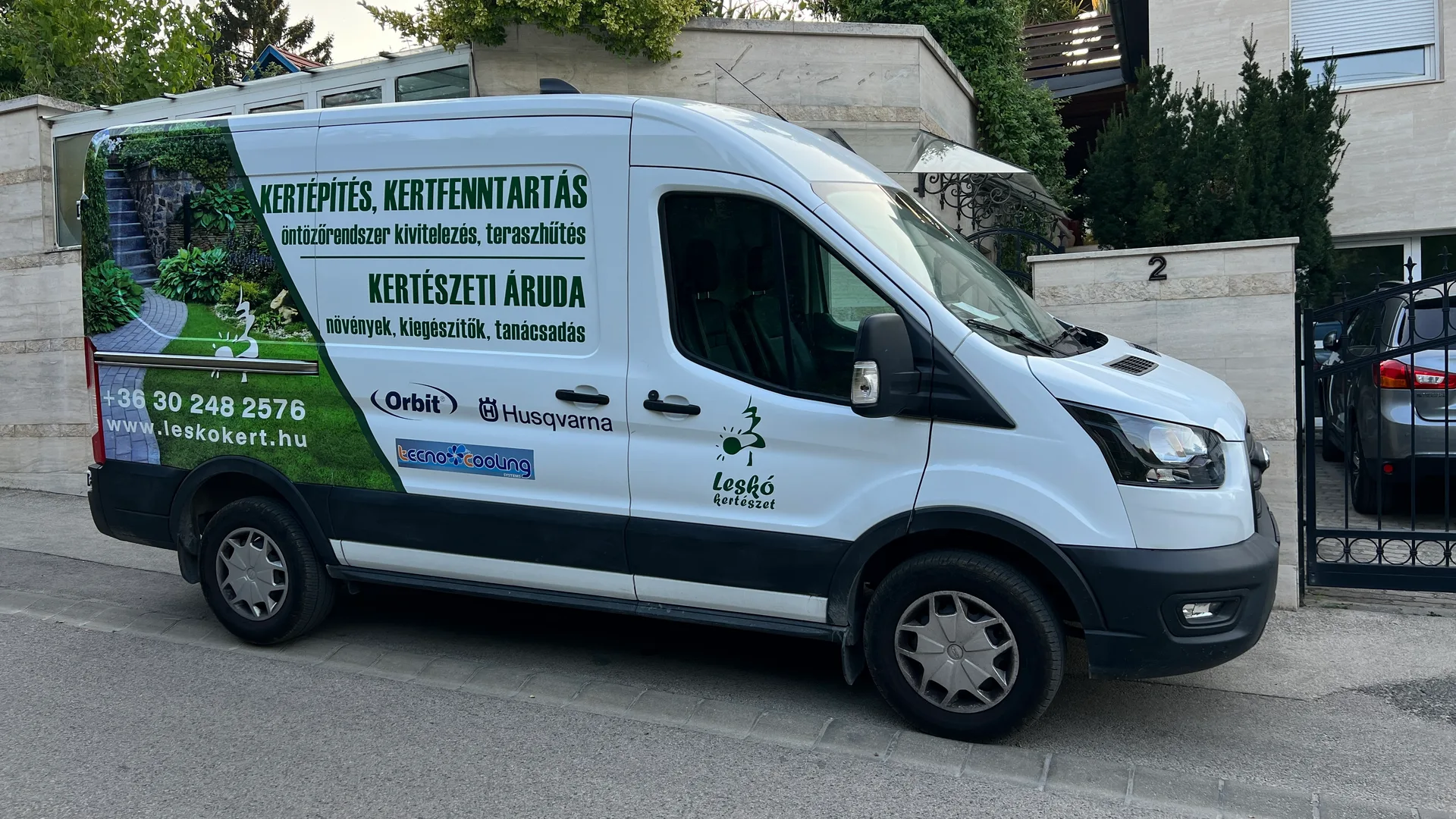 Leskó Kertészet részlegesen dekorált fehér Ford Transit haszongépjármű – fotóalapú zöld kertgrafika és vágott fóliás szolgáltatási feliratok