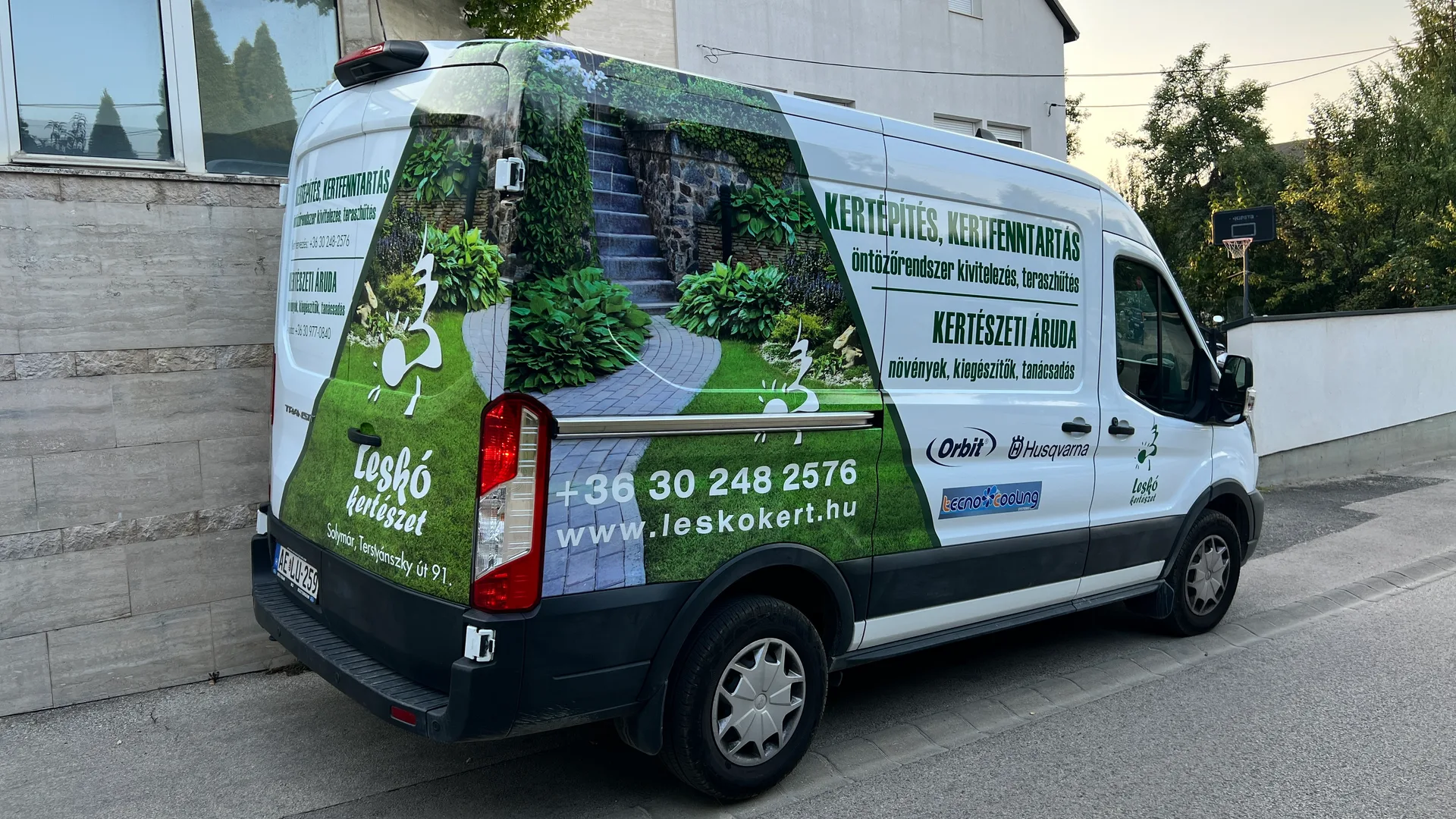 A megvalósult Leskó Kertészet Ford Transit dekoráció hátsó-oldalsó nézetből, nagyméretű kertfotóval, szolgáltatási felirattal, telefonszámmal és weboldalcímmel