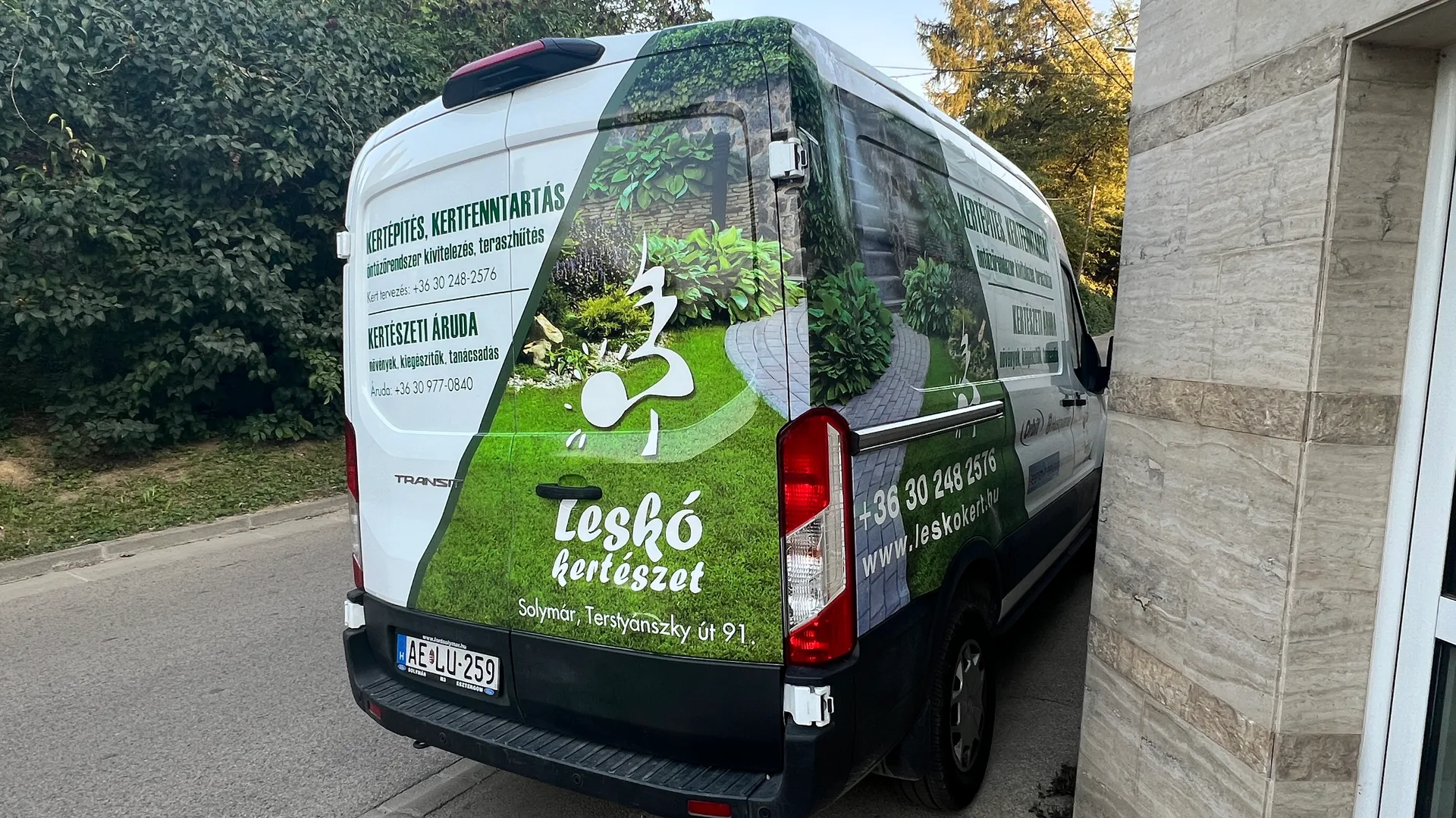A Leskó Kertészet részlegesen dekorált Ford Transit járműve hátulról, enyhén oldalirányból fényképezve – hátsó ajtókon zöld kertgrafika, logó és szolgáltatási információk