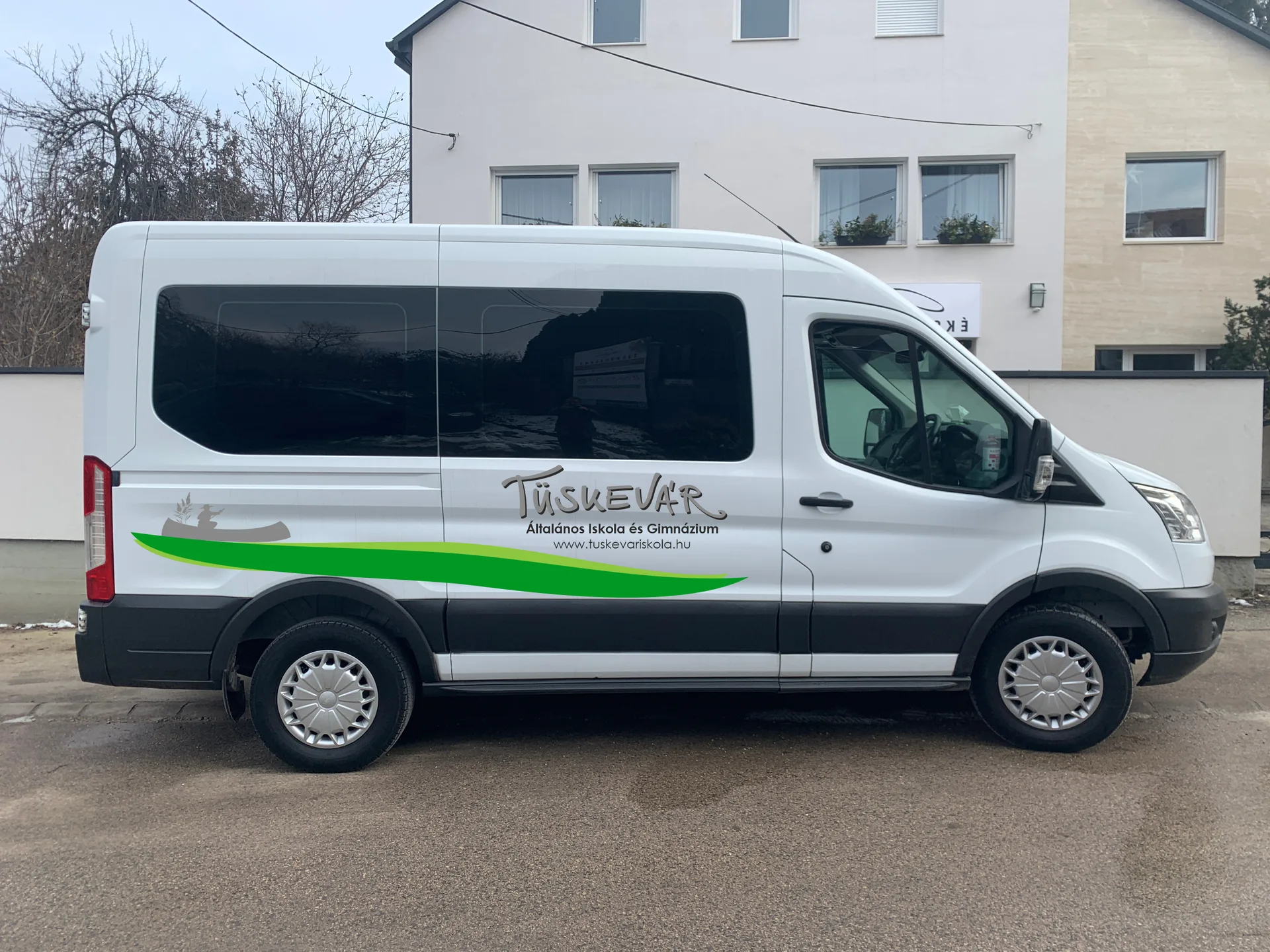 Jobb oldali látványterv a Tüskevár iskola Ford Transit buszdekorjáról, az iskola nevével, webcímével és zöld grafikai sávval