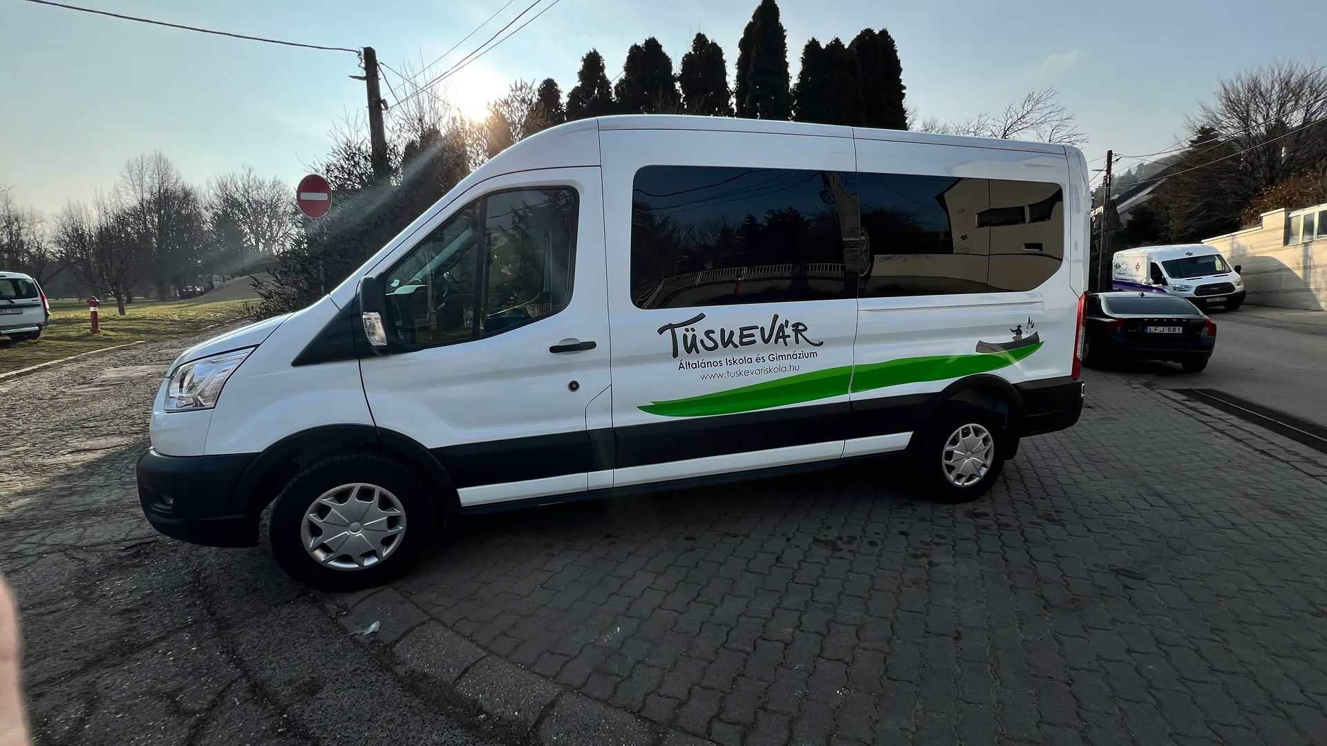 Háromnegyedes nézet a dekorált Ford Transit szállítóbuszról, a Tüskevár felirattal és zöld hullámos grafikával